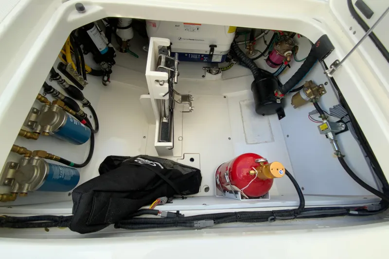 Slide: The Image of Engine compartment of 2026 Pursuit DC 326 Dual Console boat, featuring equipment and fire extinguisher. - 58