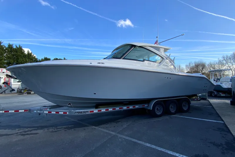 Slide: The Image of 2026 Pursuit DC 326 Dual Console boat on trailer under clear blue sky. - 6