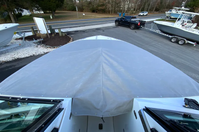 Slide: The Image of 2026 Pursuit DC 326 Dual Console boat with cover, parked near road and other boats. - 67