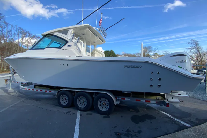 Slide: The Image of 2026 Pursuit DC 326 Dual Console boat on trailer, parked outdoors under blue sky. - 7