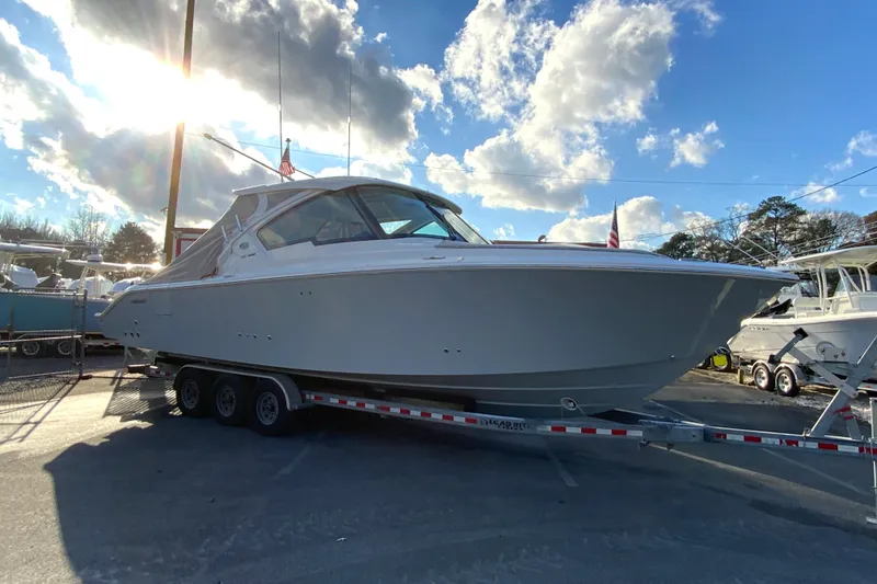 Slide: The Image of 2026 Pursuit DC 326 Dual Console boat on trailer under a bright sky. - 70