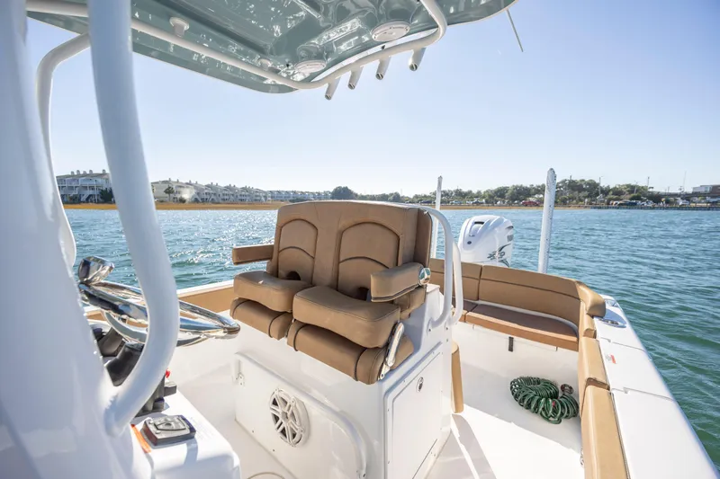 Slide: The Image of 2021 Sea Hunt Escape 27 boat interior with tan seating and steering wheel on calm water. - 19
