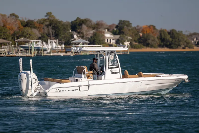 Slide: The Image of 2021 Sea Hunt Escape 27 boat cruising on a sunny day near a wooded shoreline. - 4