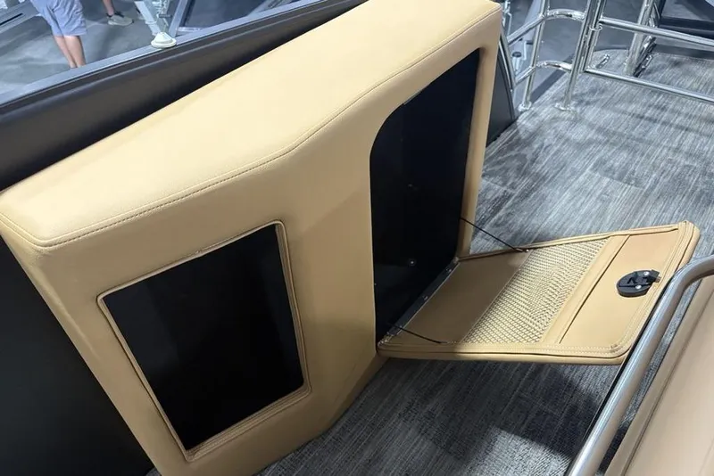 Slide: The Image of 2025 Godfrey AquaPatio 235 DFL boat interior with open storage compartment and beige upholstery. - 33