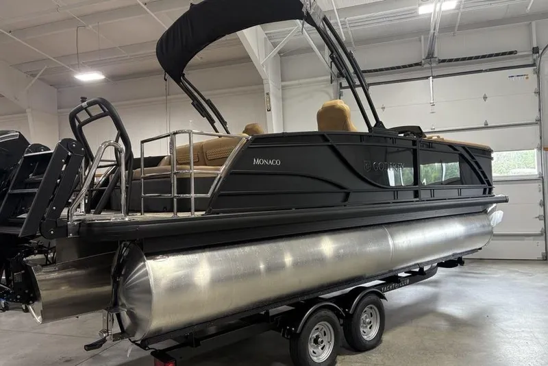 Slide: The Image of 2025 Godfrey AquaPatio 235 DFL pontoon boat in showroom, featuring sleek black design. - 4