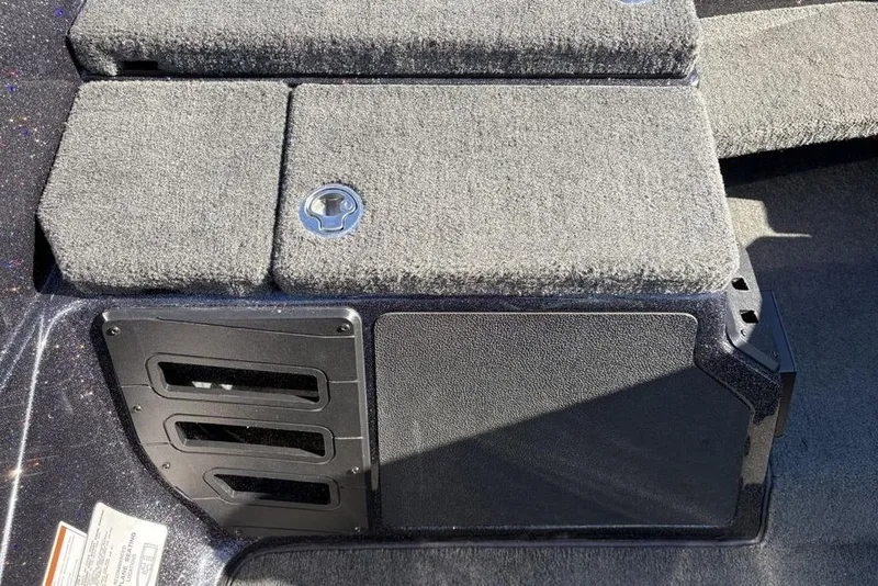 Slide: The Image of 2018 Skeeter ZX225 boat storage compartment with carpeted lid and metal latch. - 14