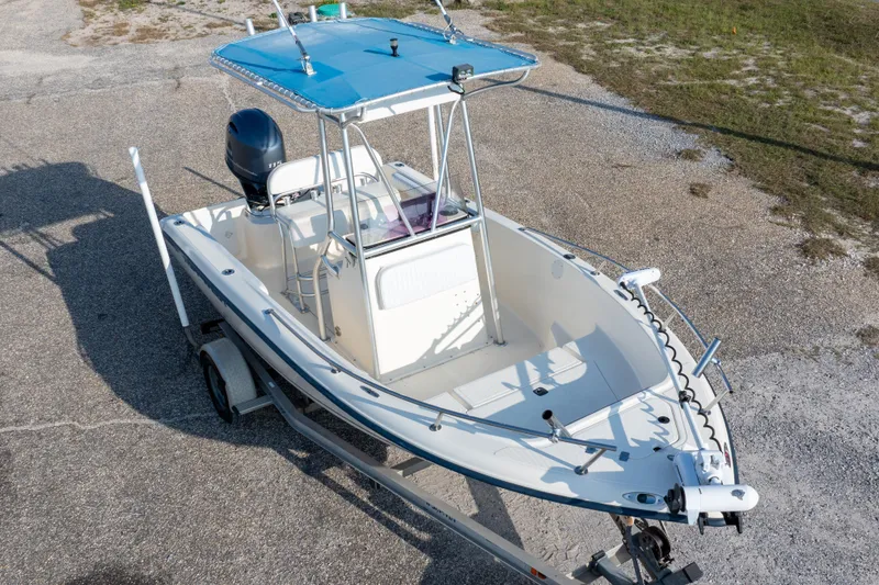 Slide: The Image of 2004 Key West 186 Center Console boat on trailer, blue canopy, parked on gravel. - 2