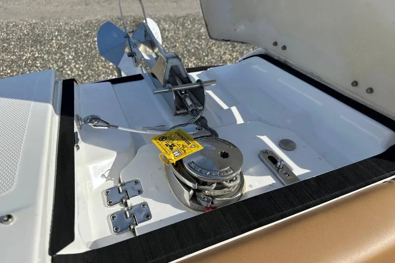 Slide: The Image of 2024 Hurricane SunDeck 2600 OB anchor compartment with winch and safety label. - 17