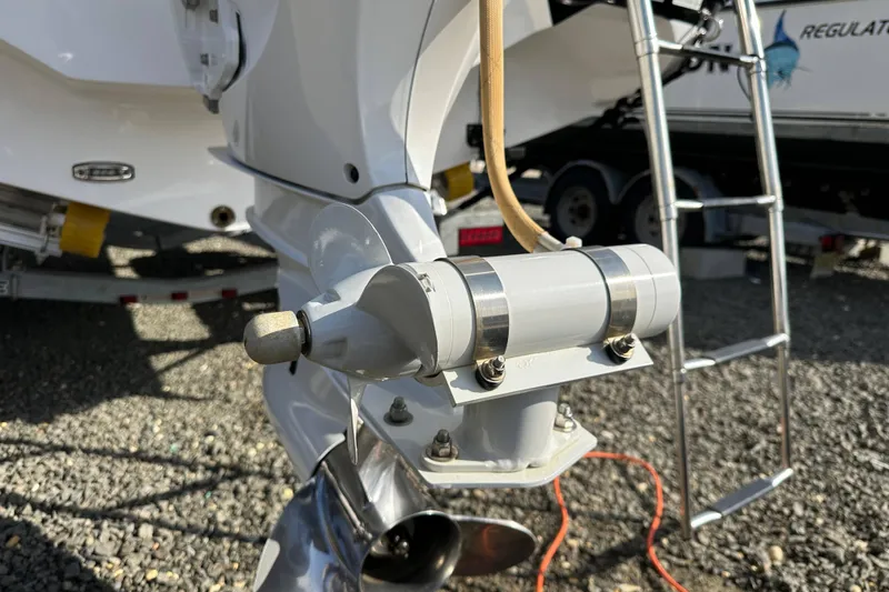 Slide: The Image of 2024 Hurricane SunDeck 2600 OB outboard motor detail with ladder and trailer in background. - 22