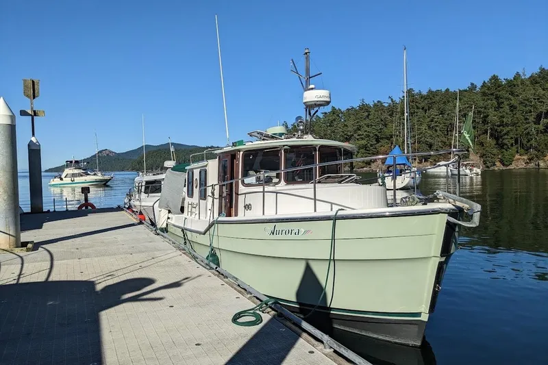 Slide: The Image of 2010 Ranger Tugs R-29 boat docked at a scenic marina with forested background. - 3