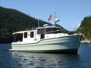 Slide: The Image of 2010 Ranger Tugs R-29 boat on calm water with forested hills. - 4
