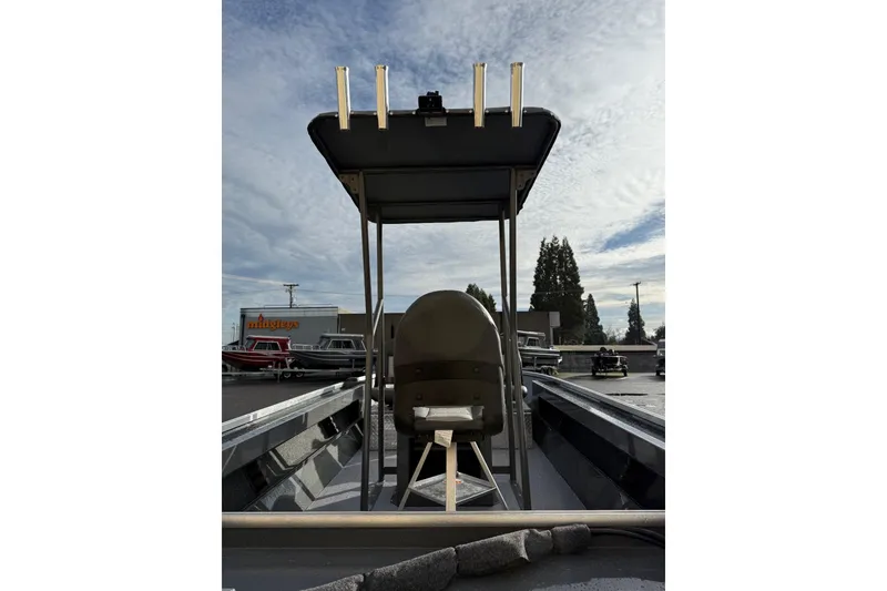 Slide: The Image of 2026 Fish Rite Angler 18 boat with T-top and seating, parked outdoors under a cloudy sky. - 13