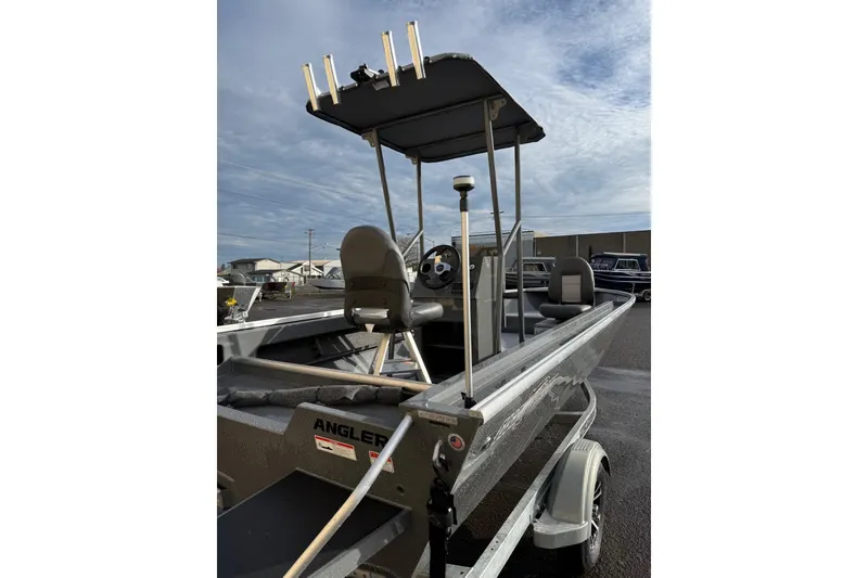 Slide: The Image of 2026 Fish Rite Angler 18 boat with canopy and seating, parked outdoors. - 14