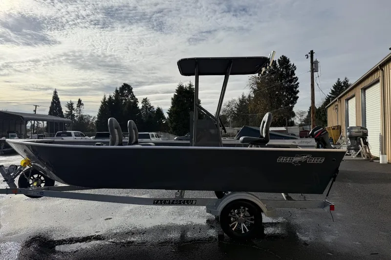 Slide: The Image of 2026 Fish Rite Angler 18 boat on trailer, parked outdoors under cloudy sky. - 2