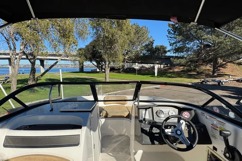 Slide: The Image of 2022 Bayliner VR6 Bowrider OB interior with steering wheel, dashboard, and scenic park view. - 45