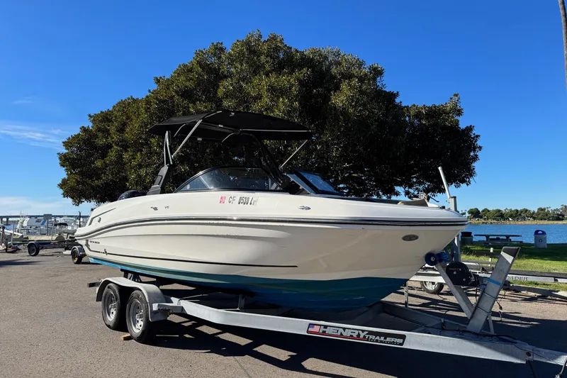 Slide: The Image of 2022 Bayliner VR6 Bowrider OB on trailer, parked near a lake under a clear blue sky. - 8