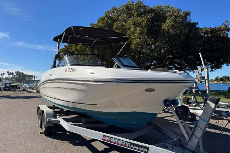 Slide: The Image of 2022 Bayliner VR6 Bowrider OB on trailer, parked near waterfront under clear blue sky. - 9
