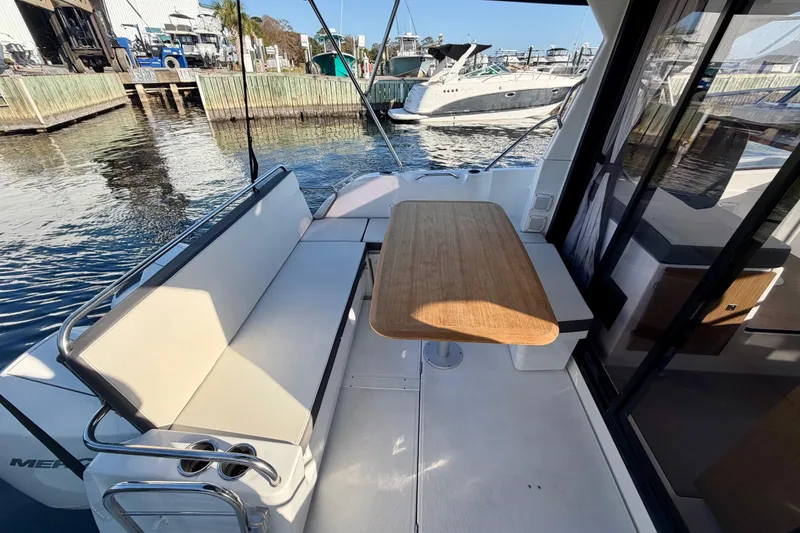 Slide: The Image of 2021 Beneteau Antares 9 boat interior with seating and wooden table by the dock. - 10