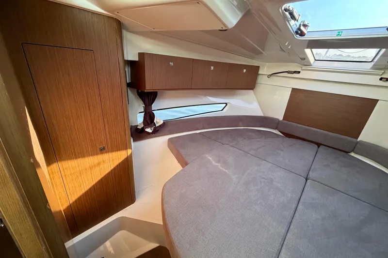 Slide: The Image of 2021 Beneteau Antares 9 cabin interior with wood paneling and gray upholstery. - 19
