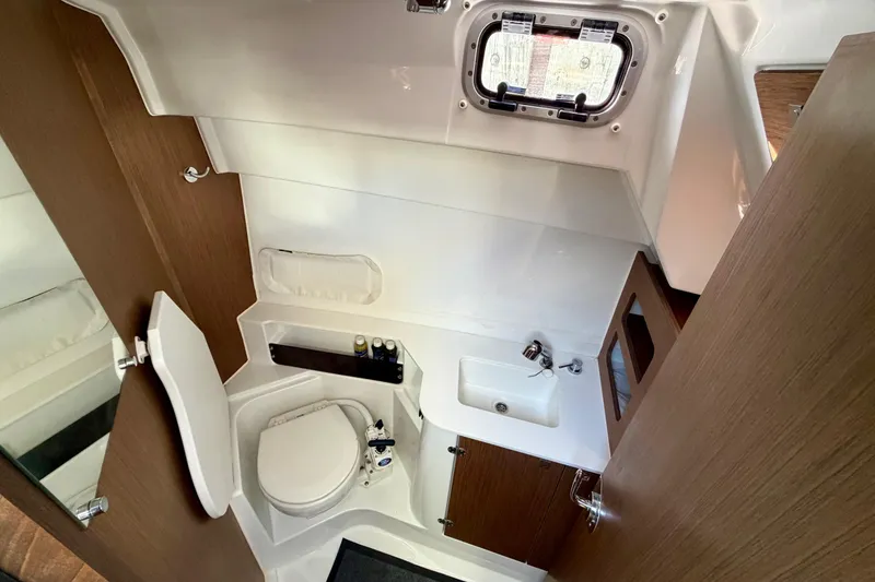 Slide: The Image of 2021 Beneteau Antares 9 bathroom interior with toilet, sink, and wooden cabinetry. - 21