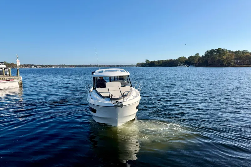 Slide: The Image of 2021 Beneteau Antares 9 cruising on a serene lake under a clear blue sky. - 8