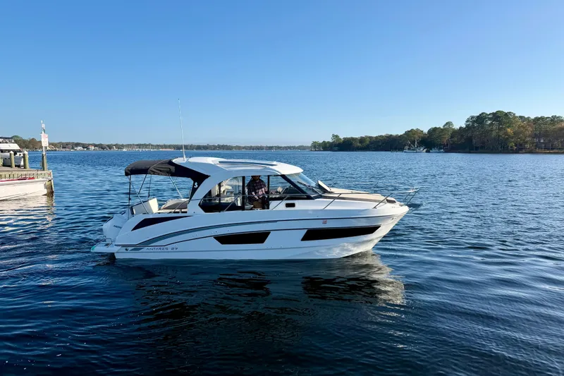 Slide: The Image of 2021 Beneteau Antares 9 cruising on a serene lake under a clear blue sky. - 9
