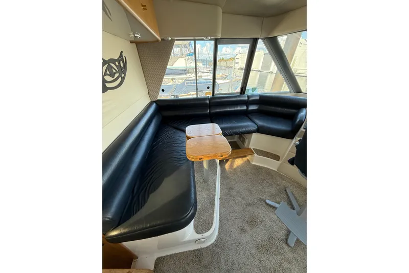 Slide: The Image of Interior of 1997 Bayliner 47 Motoryacht with black leather seating and wooden table. - 10