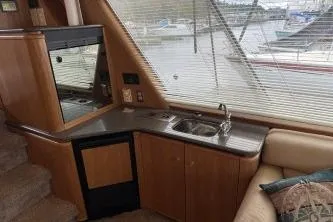 Slide: The Image of Interior of 1997 Bayliner 47 Motoryacht with kitchenette and marina view. - 17