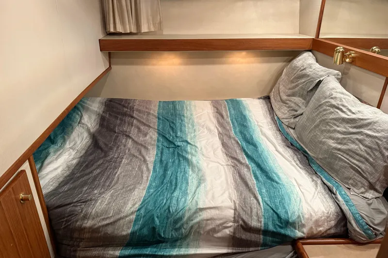 Slide: The Image of Cozy bedroom in 1997 Bayliner 47 Motoryacht with striped bedding and wooden accents. - 19