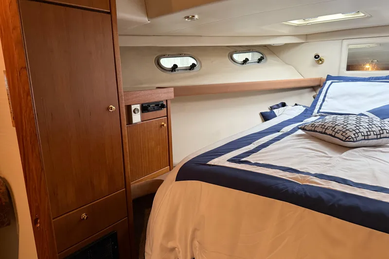 Slide: The Image of Interior of 1997 Bayliner 47 Motoryacht bedroom with wood cabinetry and nautical bedding. - 22