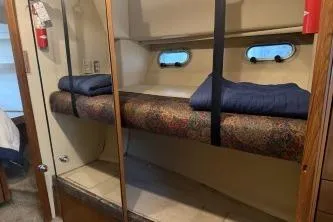 Slide: The Image of 1997 Bayliner 47 Motoryacht interior with bunk beds and porthole windows. - 25