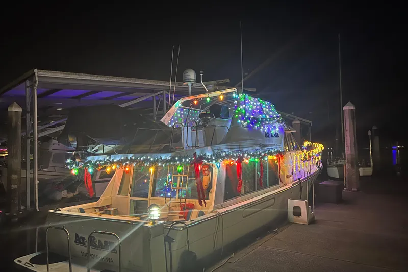 Slide: The Image of 1997 Bayliner 47 Motoryacht adorned with colorful holiday lights at night. - 30