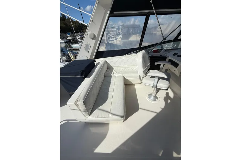 Slide: The Image of 1997 Bayliner 47 Motoryacht helm with white seating and control panel. - 4