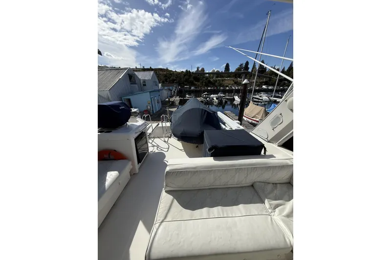 Slide: The Image of 1997 Bayliner 47 Motoryacht deck view with marina backdrop under blue sky. - 6