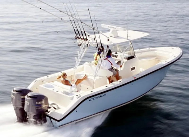Slide: The Image of 2016 Cobia 296 Center Console boat in a well-lit garage with fishing gear. - 2