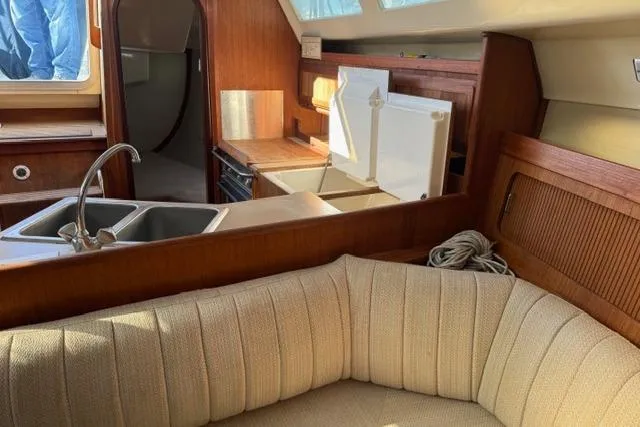 Slide: The Image of 1989 Hunter 35.5 sailboat cabin interior with beige cushions and a red storage box. - 6