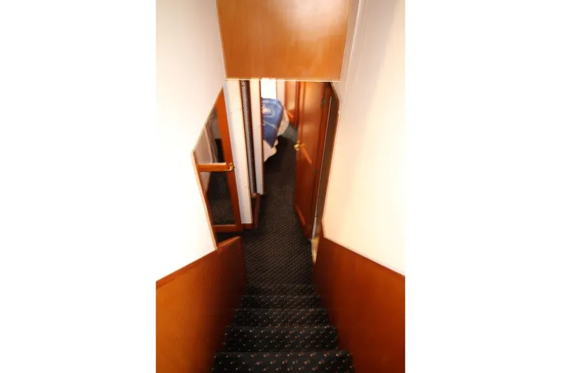 Slide: The Image of Stairway inside 1999 Ocean Yachts 60 Super Sport, featuring wooden paneling and carpeted steps. - 46