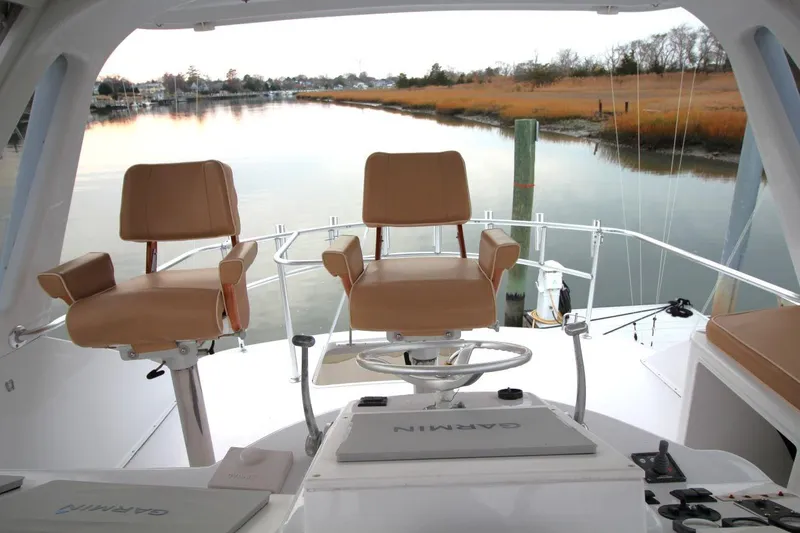 Slide: The Image of 1999 Ocean Yachts 60 Super Sport helm with dual captain chairs overlooking serene waterway. - 25