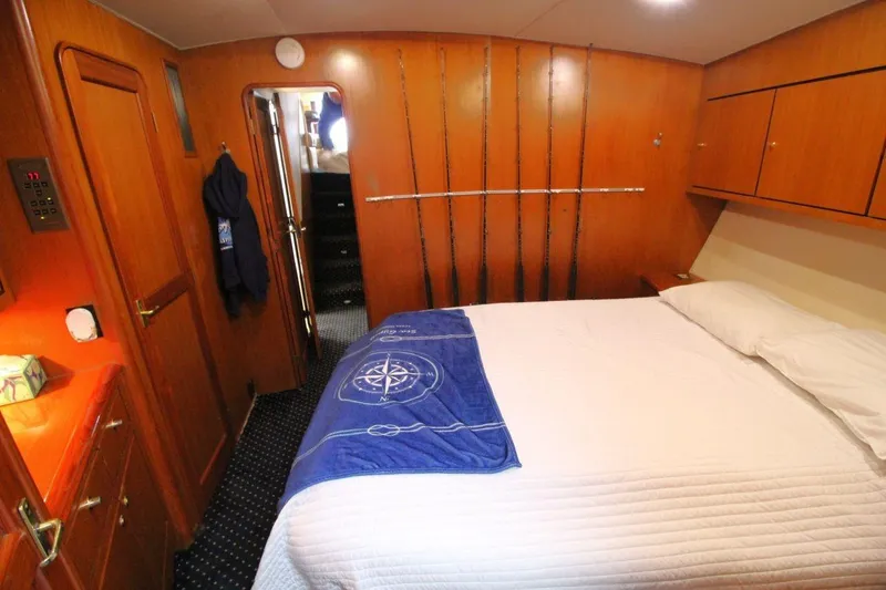 Slide: The Image of Cozy bedroom in 1999 Ocean Yachts 60 Super Sport with wooden cabinetry and fishing rods. - 56