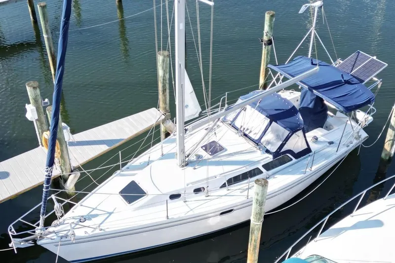 Slide: The Image of 2003 Catalina 320 sailboat docked, featuring blue covers and solar panels. - 2