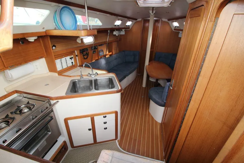 Slide: The Image of Interior of 2003 Catalina 320 sailboat with kitchen, seating area, and wooden finishes. - 20
