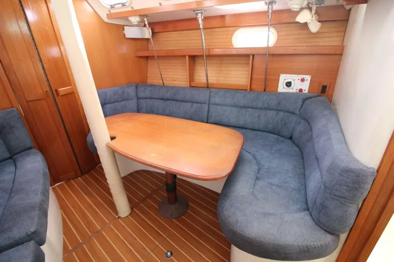 Slide: The Image of Interior of 2003 Catalina 320 sailboat with blue cushioned seating and wooden table. - 22
