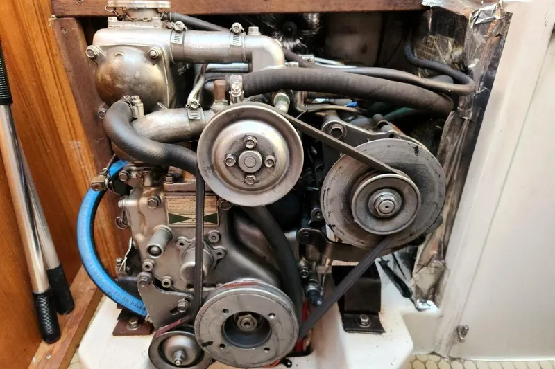 Slide: The Image of Catalina 320 2003 engine with visible belts and hoses in a wooden compartment. - 30