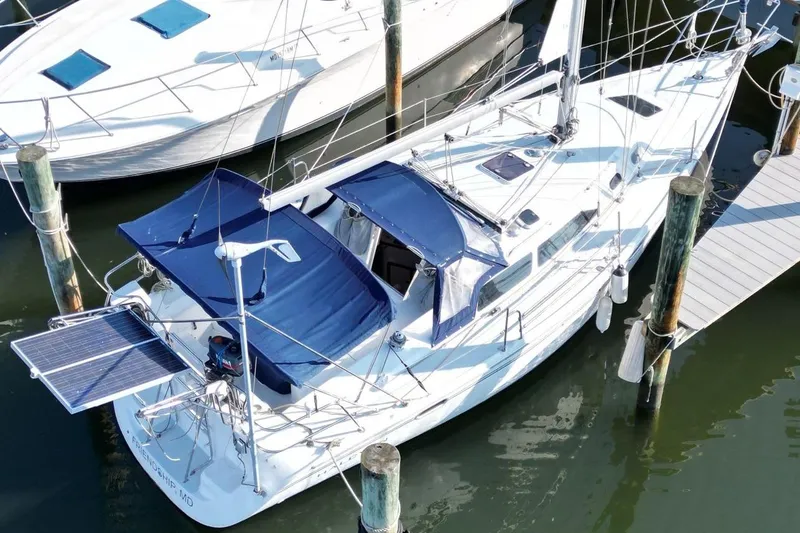 Slide: The Image of 2003 Catalina 320 sailboat docked, featuring blue canopies and solar panels. - 4