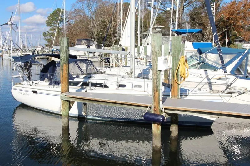 Slide: The Image of 2003 Catalina 320 sailboat docked at a marina with clear skies and calm waters. - 5