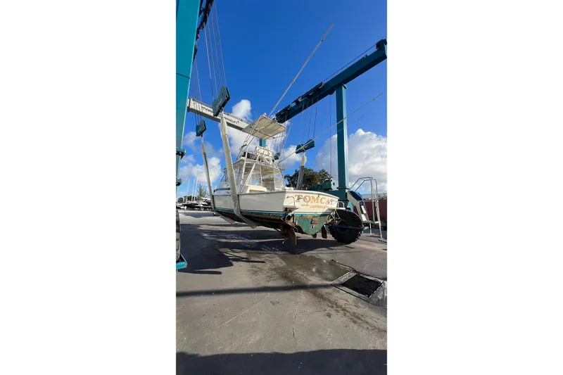 Slide: The Image of 1968 Bertram 31 Bahia Mar boat lifted by crane under blue sky. - 26