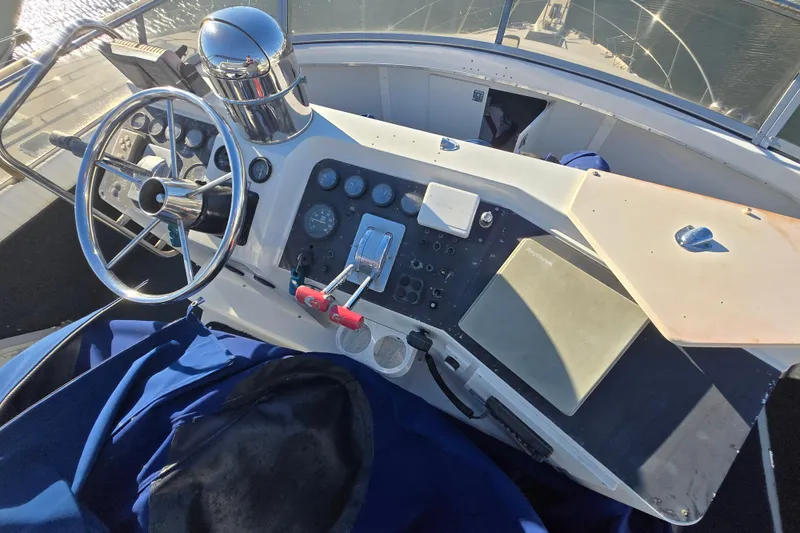 Slide: The Image of 1995 Carver 430 Cockpit Motor Yacht helm with steering wheel and control panel. - 32