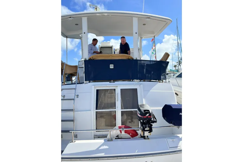 Slide: The Image of 1999 Carver 430 Cockpit Motor Yacht with two people on deck, docked at marina. - 43
