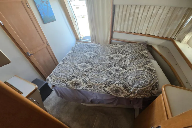 Slide: The Image of Cozy bedroom in 1995 Carver 430 Cockpit Motor Yacht with patterned bedding and natural light. - 22
