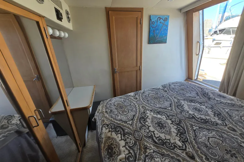 Slide: The Image of Interior of 1995 Carver 430 Cockpit Motor Yacht bedroom with patterned bedding and wooden accents. - 24